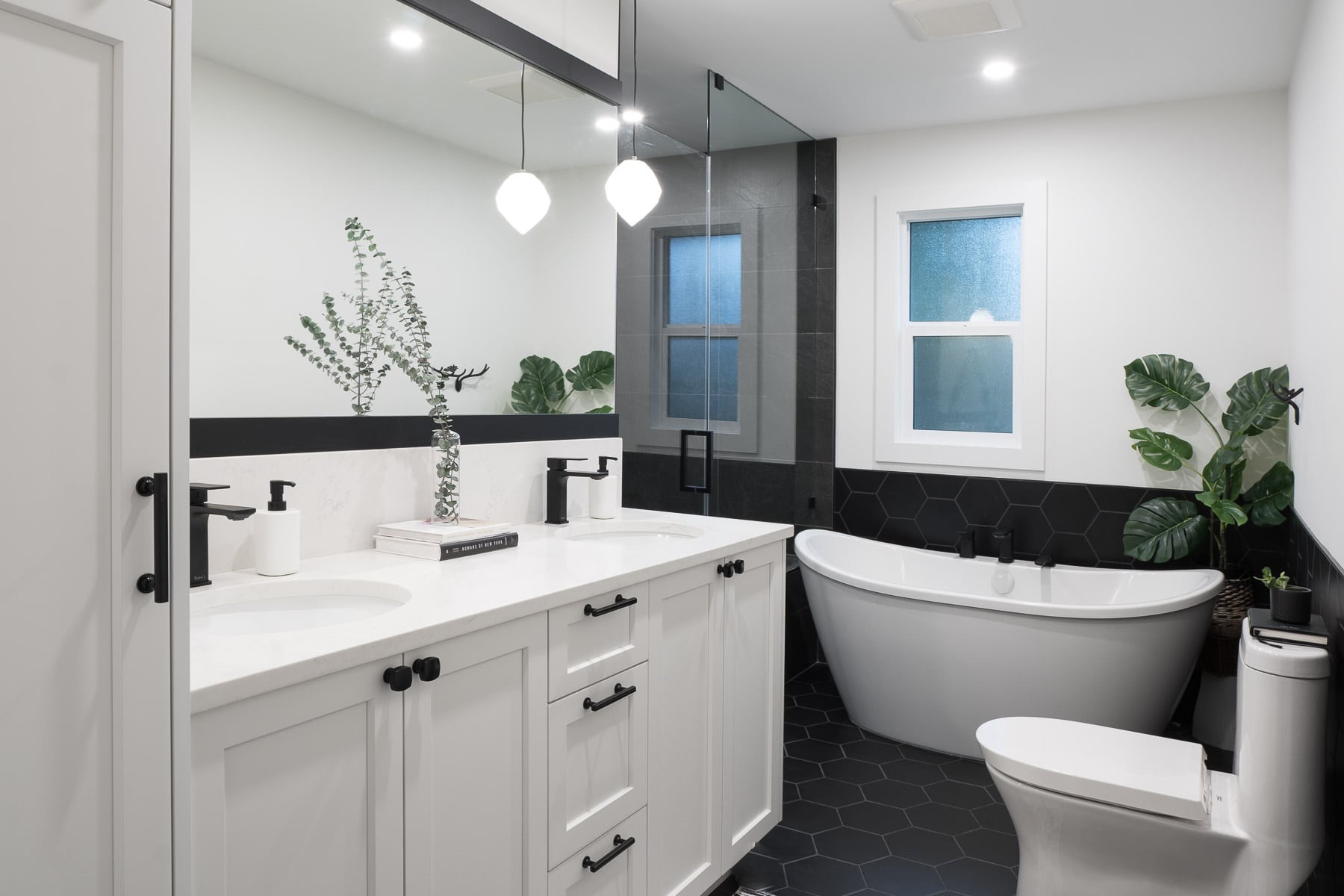 Bathroom with 7 x 8" black matte hex tile on floor and wainscotting; double slipper tub, walk-in shower, pendant lighting, vanity and closet tower.